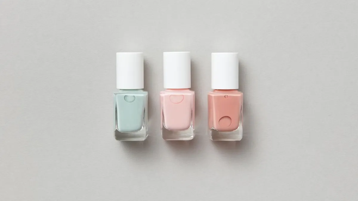 Three pastel nail polish bottles tidily arranged on grey