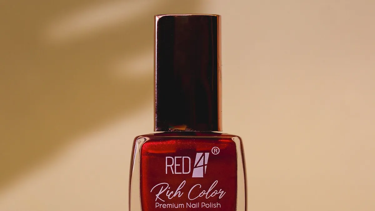 A single red nail polish bottle on a white surface