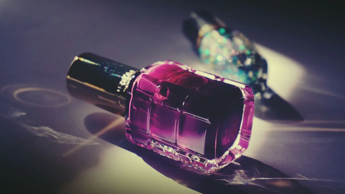 A single nail polish bottle lit on a dark surface