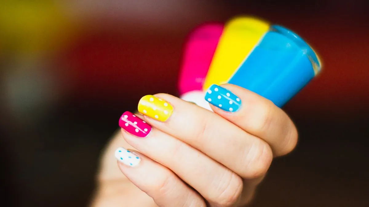 A hand holding several colorful nail polish bottles