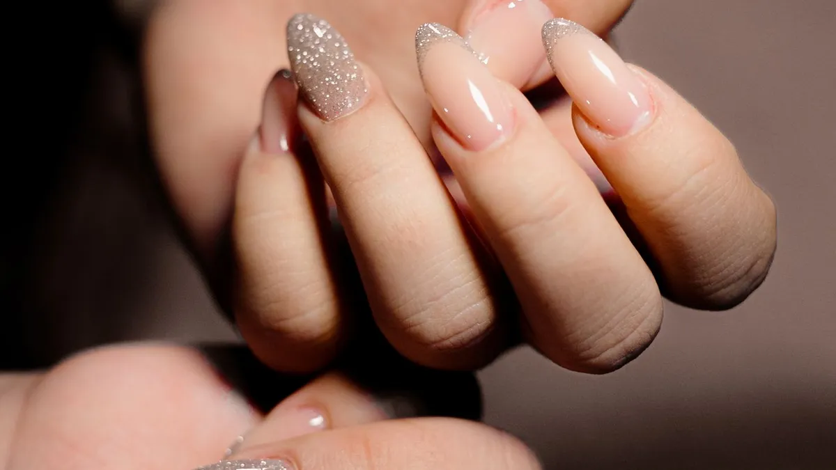 Manicured nails with a nude base and glitter accent