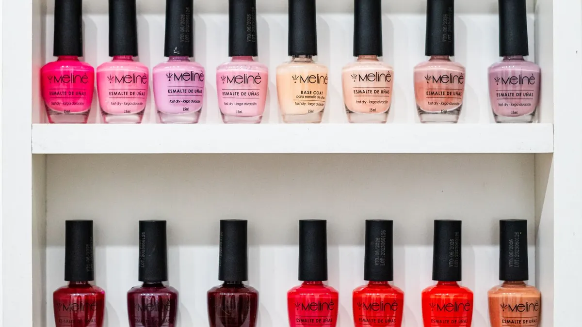 Nail polish bottles arranged by color on a white shelf