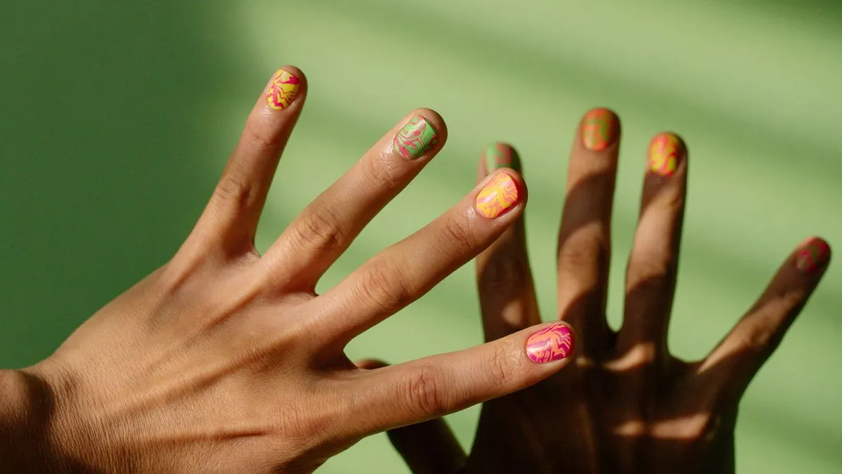 Five fingernails each painted a different bright color