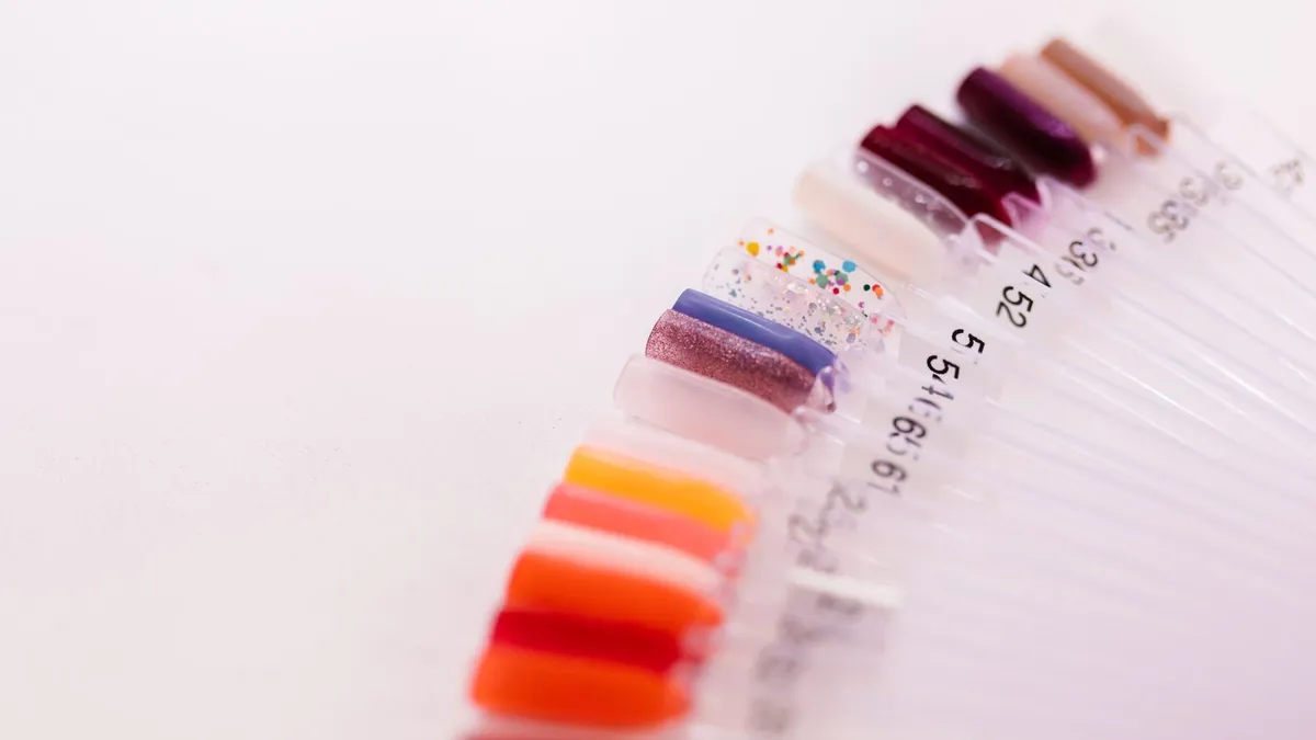 Fan of numbered nail polish swatch sticks in assorted colors on a pale background